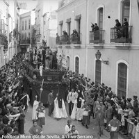 11. JUAN JOSÉ SERRANO GÓMEZ. Misterio de la Sagrada Cena a su paso por el cuartel de la Guardia Civil de la calle Gerona. 1938.  Es el paso de misterio con mayor número de figuras de la Semana Santa sevillana. A causa del incendio de la iglesia de Omnium Sanctorum en 1936, la Hermandad de la Cena se establece en la de Los Terceros. En plena Guerra Civil, el público saluda brazo en alto al paso por el cuartel. © ICAS-SAHP, Fototeca Municipal de Sevilla, Archivo Serrano