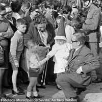 20. RAFAEL CUBILES LÓPEZ. Salida de la Hermandad de San Roque en la plaza de Carmen Benítez. 1968.  La tradición es uno de los pilares sobre los que se asienta el hecho religioso y su continuidad se refuerza a través del arraigo familiar a la hermandad de tus mayores y de la transmisión del rito de padres a hijos y de abuelos a nietos.  © ICAS-SAHP, Fototeca Municipal de Sevilla, Archivo Cubiles