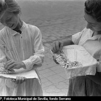 Jóvenes preparando una bandeja de moñas de jazmines para su venta al anochecer. 1955-1960 ©ICAS-SAHP, Fototeca Municipal de Sevilla, fondo Serrano