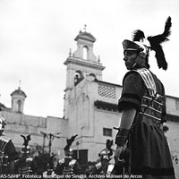 14. MANUEL DE ARCOS. Centuria Romana de la Hermandad del Santo Entierro en la plaza Virgen de los Reyes. 1959.   Rescatada para el cortejo en el siglo XIX, es un resto de las dramatizaciones del pasaje del Entierro. Los componentes del escuadrón, con su capitán al frente, se presentan ataviados con una fiel reproducción de la usanza romana del siglo I.  © ICAS-SAHP, Fototeca Municipal de Sevilla, Archivo Manuel de Arcos